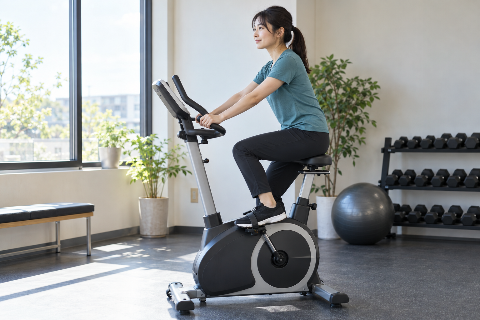 明るい室内でエアロバイクをこぐ女性のイメージ